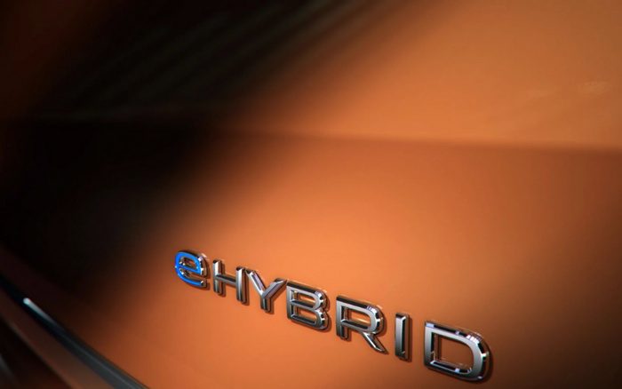 Close-up image of a car badge reading 'eHYBRID' on an orange vehicle, highlighting eco-friendly hybrid technology suitable for customers interested in used cars and new cars.
