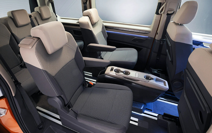 Interior view of a modern vehicle showcasing three rows of comfortable seats with grey and black upholstery, featuring adjustable headrests and armrests. The image highlights the spacious cabin with individual seating and a central console between the front seats, suggesting a focus on comfort and functionality, relevant to used cars and new cars.