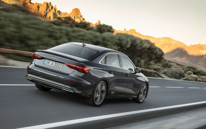 Grey Audi A3 sedan driving on a mountain road at sunset, showcasing sleek design and modern tail lights, ideal for buyers interested in used cars or new cars.