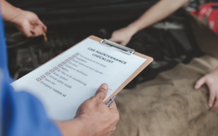 Technician holding a vehicle maintenance checklist