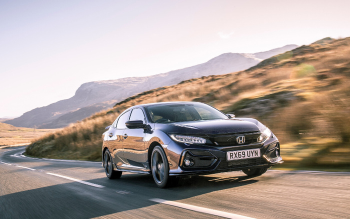 Black Honda Civic hatchback with registration RX69 UYN driving on a winding road through a scenic mountainous landscape during daylight, suitable image for used cars and new cars promotion.
