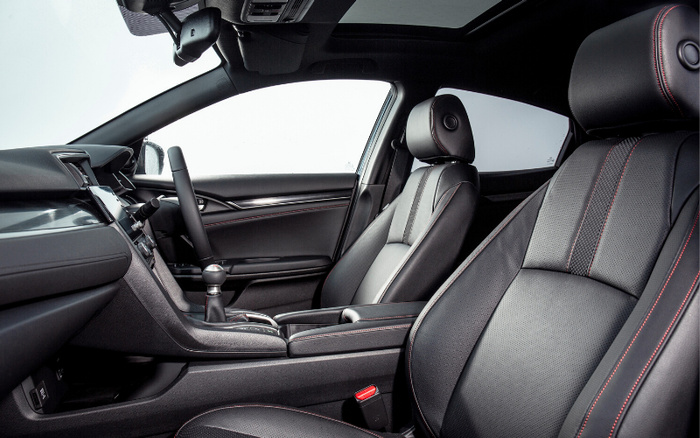 Interior of a modern car showcasing black leather seats with red stitching, a black steering wheel, dashboard, and centre console, highlighting the comfort and design typical of new cars and used cars available on the market.