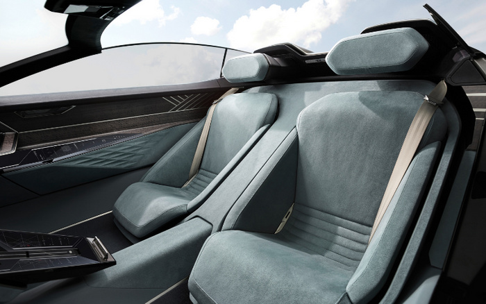 Interior of a modern car showcasing two stylish grey suede seats with integrated headrests and beige seatbelts, surrounded by sleek black and wooden dashboard panels with digital controls, highlighting luxury and advanced design, suitable for used cars and new cars buyers.