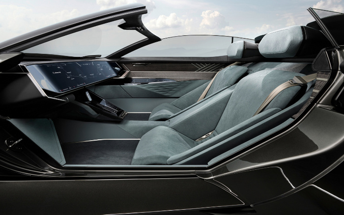 Interior of a modern luxury car showcasing a sleek dashboard with a large digital display screen showing navigation, and two blue-grey upholstered seats with seatbelts, highlighting features relevant for used cars and new cars buyers.