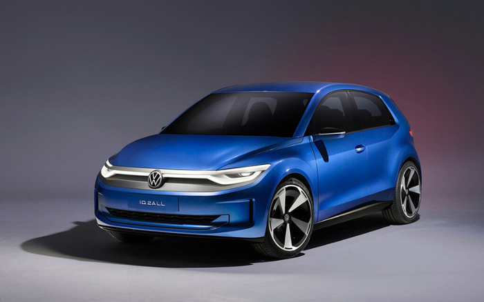 Blue Volkswagen electric car model IQ.DRIVE parked in a studio setting with smooth grey background, featuring sleek aerodynamic design, distinctive LED headlights connecting with the Volkswagen logo on the grille, and sporty black and silver alloy wheels, suitable for advertising used cars and new cars.