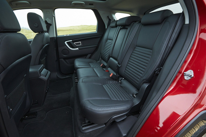 Back seat interior of a new red car featuring black leather seats with ribbed detailing, three seatbelt buckles, and headrests, showcasing spacious seating area ideal for family or group travel, highlighting quality and comfort in used cars and new cars.
