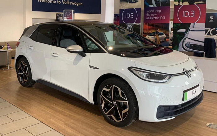 White Volkswagen ID.3 electric car displayed inside a Volkswagen showroom with wooden flooring. Background features posters reading 'Welcome to Volkswagen', 'ID.3', and 'Introducing the new all-electric ID.3'. The front license plate shows 'ID.3'. This image represents new cars, specifically the Volkswagen ID.3 electric vehicle, available alongside used cars at the dealership.
