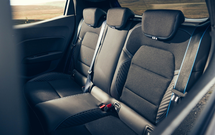 Interior view of the back seats of a modern car featuring black and dark grey fabric upholstery with distinct stitching and integrated headrests, showcasing clean and spacious seating suitable for passengers, relevant for used cars and new cars.