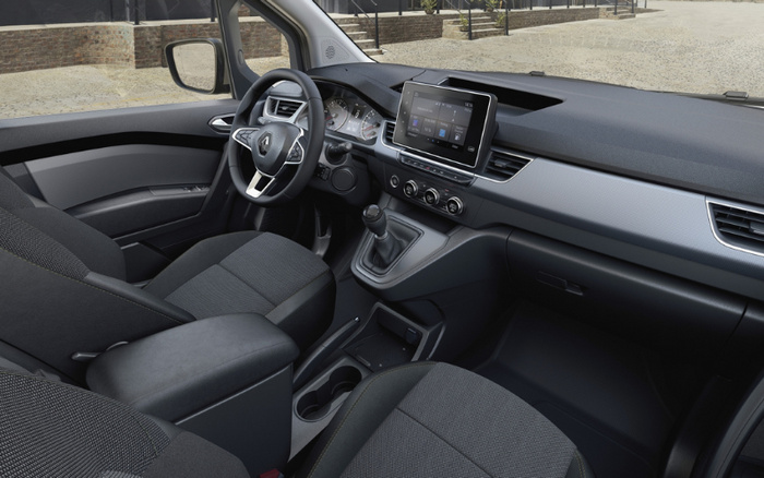 Interior view of a modern Renault car showcasing the driver's seat, steering wheel with Renault logo, manual gear shift, and touchscreen infotainment system displaying media and navigation options. The dashboard features climate control knobs and sleek air vents, with fabric upholstery on the seats. This interior represents a comfortable and stylish option for both used cars and new cars buyers.