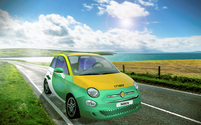Green and yellow compact car on a coastal road with a scenic view of ocean and fields under a partly cloudy sky. The car has the numbers '171803' on the front hood and a license plate reading '345OUTH'. Ideal image representing used cars and new cars in a scenic driving environment.