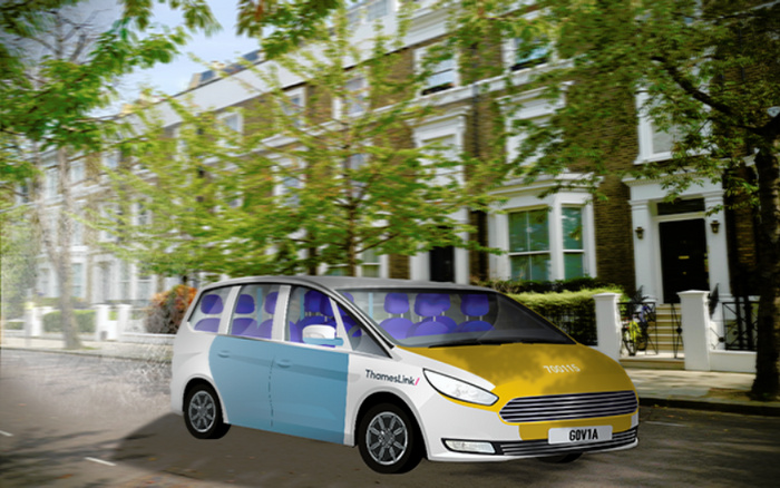 Thameslink transit vehicle with distinct yellow front and light blue side panel driving on a residential street with terraced houses and trees, featuring text 'ThamesLink' on the side and a license plate reading 'GOV1A'. The image relates to new cars and used cars in an urban environment.