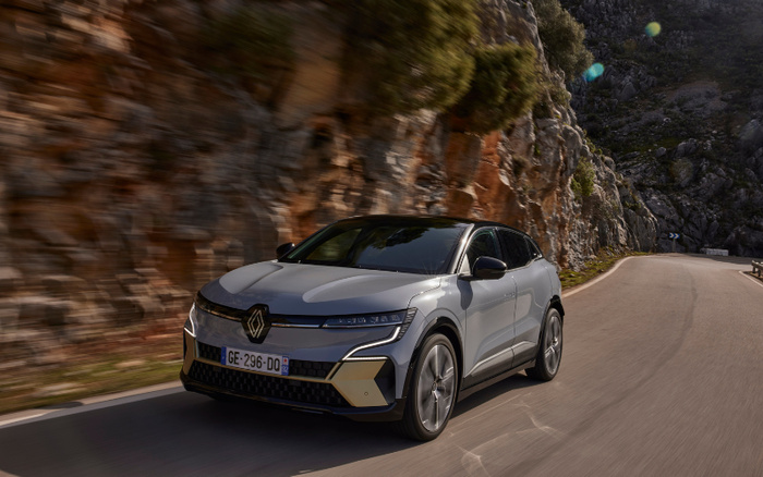 Silver Renault electric car with French license plate GE-296-DD driving on a winding road next to rocky cliffs under daylight, suitable for used cars and new cars categories.