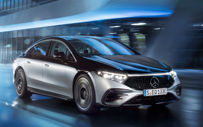 Sleek black and silver Mercedes-Benz EQ electric car driving at night in an urban setting with motion blur, showcasing modern design and LED headlights, license plate reads 'S EQ 133E', representing new cars and used cars in a futuristic environment.