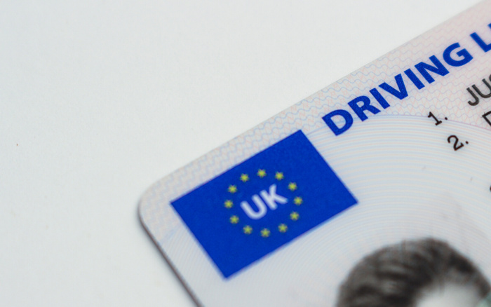 Close-up of a UK driving licence card showing the UK flag with European stars and partial text reading 'DRIVING LICENCE', symbolising legal driving credentials needed for operating new cars and used cars in the UK.