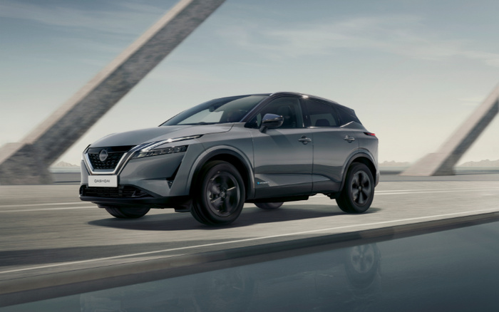 Grey Nissan Qashqai new car driving on a modern bridge with concrete supports, shown in profile view against a clear sky, highlighting sleek design and black alloy wheels, ideal for buyers interested in used cars or new cars.