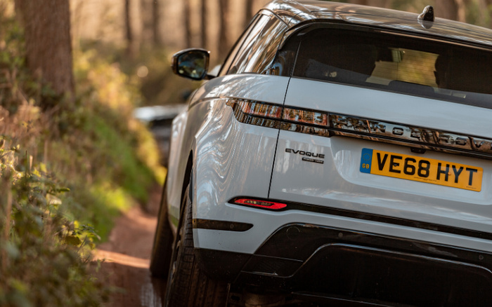 Rear view of a white Range Rover Evoque with UK license plate VE68 HYT driving on a muddy off-road forest trail, showcasing used cars and new cars in rugged outdoor conditions.
