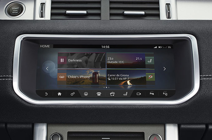 Car dashboard touchscreen display showing home screen with music playback titled Darkness paused, temperature settings 23.0°C inside and 15°C outside, a connection to Chloe's iPhone, and navigation directions to Carrer de Girona at 15:51 via AP-7. The image highlights modern infotainment system in a vehicle, relevant for used cars and new cars.