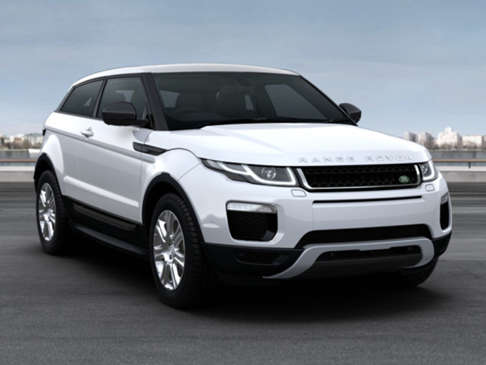White Range Rover Evoque parked outdoors with city skyline in the background, showcasing modern design and sleek headlights, ideal for used cars and new cars enthusiasts.