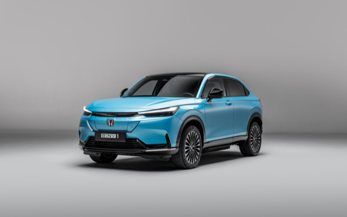 Blue Honda e:Ny1 electric SUV new car on a grey background, featuring sleek LED headlights, black roof, and aerodynamic design, showcasing a modern and stylish vehicle suitable for buyers interested in new cars or used cars.