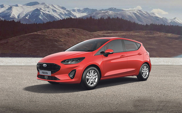 Red Ford Fiesta hatchback car parked on a paved surface with snow-capped mountains and forested hills in the background, showcasing a sleek design ideal for used cars and new cars.