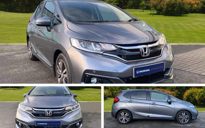 Grey Honda Jazz car parked on a driveway with green grass and trees in the background, shown from front and side angles. The car features a 'HONDA APPROVED' plate, indicating it is part of Honda's approved used cars or new cars programme. The vehicle is clean and polished, highlighting its sleek design and alloy wheels.