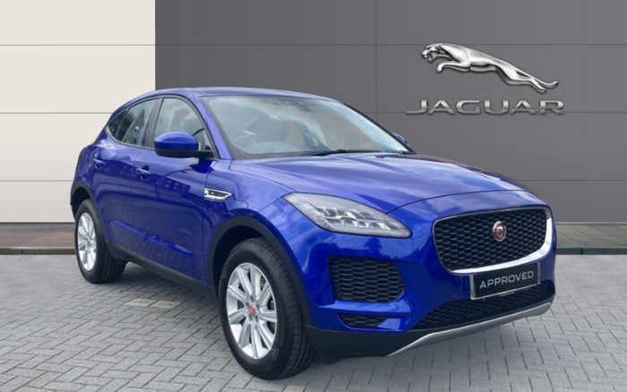 Blue Jaguar SUV displayed in front of a wall with the silver Jaguar logo and text. The car has a license plate that reads 'APPROVED', indicating a certified used car. The image showcases a premium vehicle suitable for buyers interested in used cars or new cars from Jaguar.