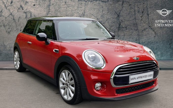 Red MINI Cooper car with black roof and side mirrors parked on a street in front of a textured wall, featuring a license plate reading '100% APPROVED USED' and a logo in the top right corner stating 'APPROVED USED MINI', highlighting both used cars and new cars options.