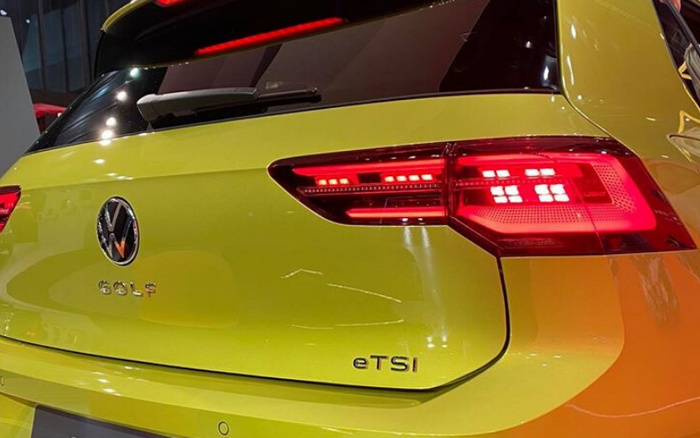 Rear view of a bright yellow Volkswagen Golf eTSI showing the Volkswagen logo, model name 'GOLF', and badge 'eTSI' near the illuminated rear tail light, representing a new car option in the used cars and new cars market.