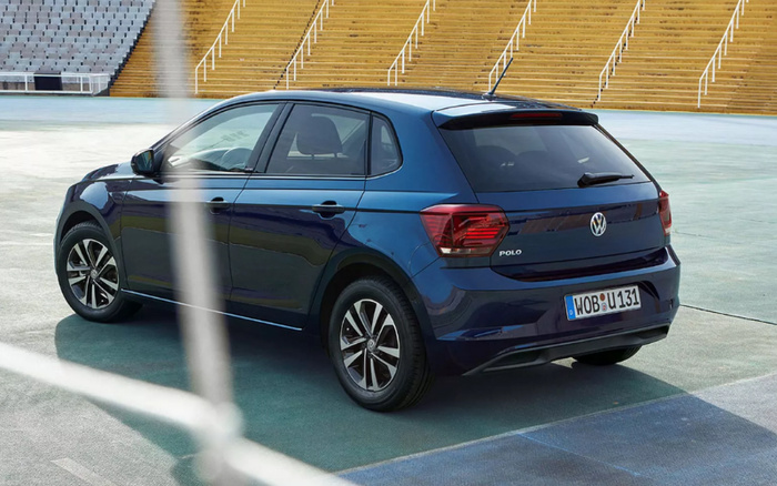 Rear and side view of a blue Volkswagen Polo hatchback parked in an empty stadium with yellow and grey seating. The car has a German license plate reading WOB U 131, and the Polo badge is visible on the rear. This image showcases a model suitable for buyers looking for used cars or new cars.