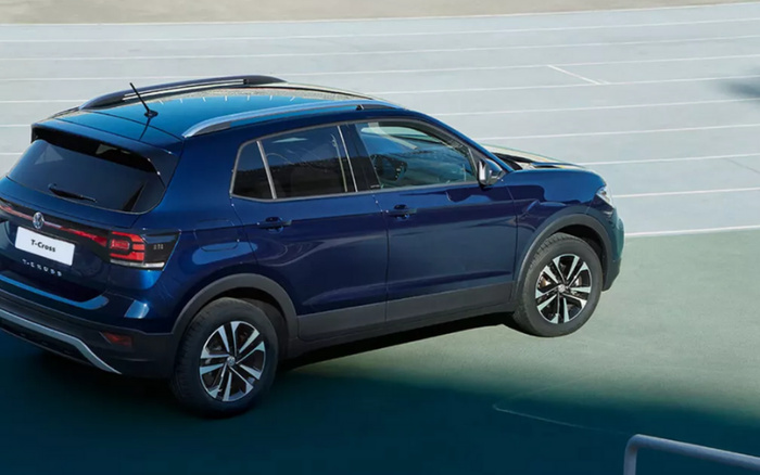 Dark blue Volkswagen T-Cross SUV parked in an empty outdoor car park with clear lane markings, showcasing the rear and side view of the vehicle, ideal for used cars and new cars listings.