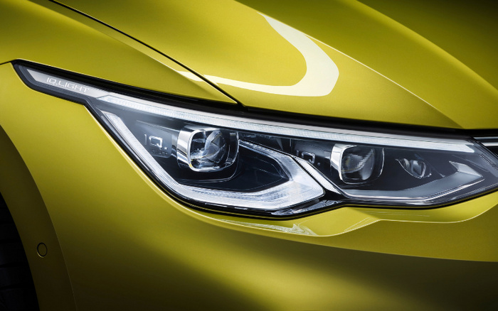 Close-up of a modern car's headlight on a yellow-green vehicle featuring 'IQ.LIGHT' branding on the LED headlight. The image showcases advanced car lighting technology, relevant for used cars and new cars.