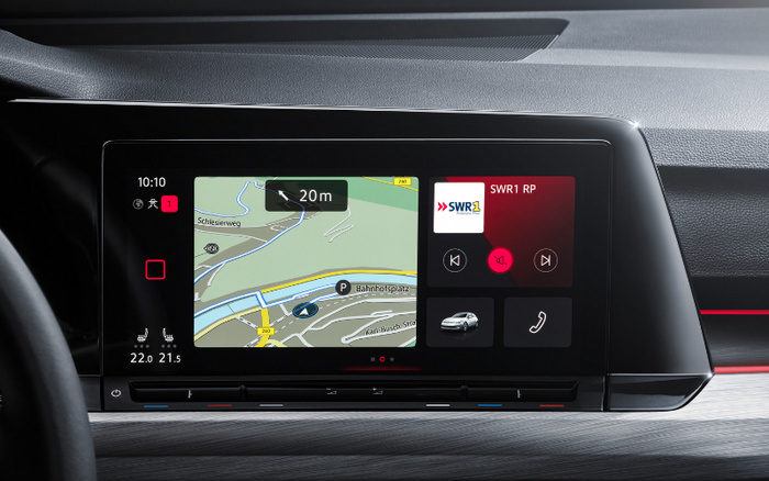 Close-up of a car's digital dashboard display screen showing a navigation map with directions and location names including Schiesierweg and Bahnhofsplatz. The screen also displays the time at 10:10, temperature controls set to 22.0 and 21.5 degrees, and a media player tuned to SWR1 RP radio station with playback controls and a mute icon. The dashboard design suggests a modern vehicle, relevant for used cars or new cars buyers exploring advanced in-car technology features.