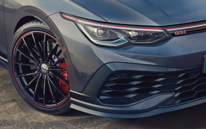Close-up of the front left side of a grey Volkswagen GTI car highlighting the headlight with red detailing labeled 'IQ.LIGHT', the red GTI badge on the front grille, and stylish black alloy wheel with red brake calipers and red rim accents, ideal for used cars and new cars enthusiasts.