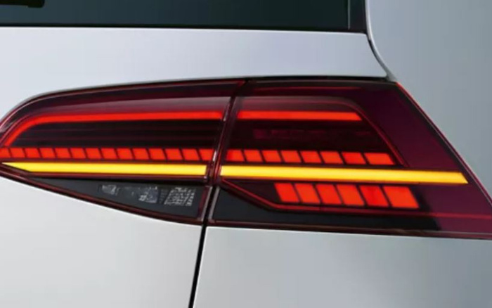 Close-up of a modern car's rear tail light featuring sleek red and amber LED light strips on a white vehicle, highlighting design details relevant for used cars and new cars.