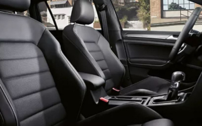 Interior view of a car showing black leather front seats, centre console with gear shift, and steering wheel. The image highlights the modern, clean design of the vehicle's cabin, suitable for advertising used cars and new cars.