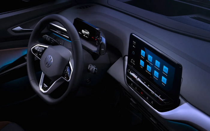 Interior view of a modern Volkswagen car showing a close-up of the steering wheel with the VW logo and digital dashboard display, alongside a touchscreen infotainment system displaying icons such as Radio, Music, Navigation, Phone, App-Connect, Vehicle, and Settings, highlighting advanced technology features in new cars and used cars.