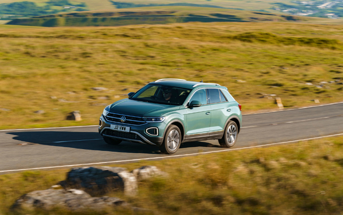 Green Volkswagen SUV driving on a countryside road with grassy hills in the background, featuring the registration plate J2 VWM, representing new cars and used cars available for sale.