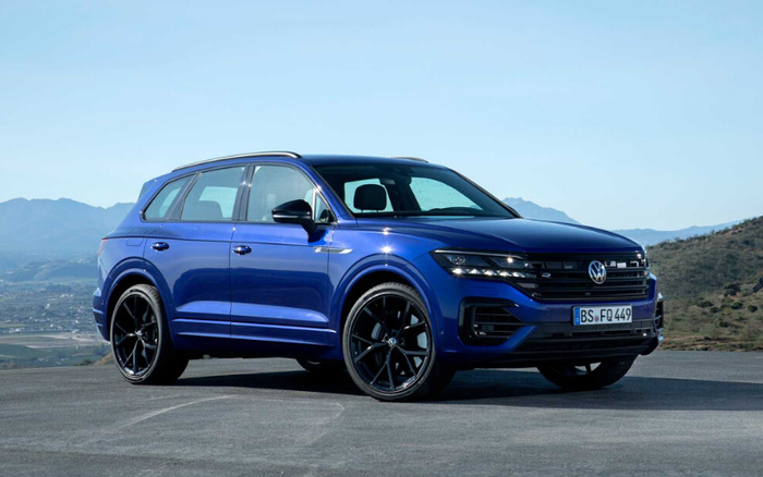 Blue Volkswagen Touareg SUV parked on a paved surface with mountainous landscape in the background and a clear blue sky. The car has black alloy wheels and a German license plate reading BS FQ 449. Suitable for used cars and new cars search keywords.