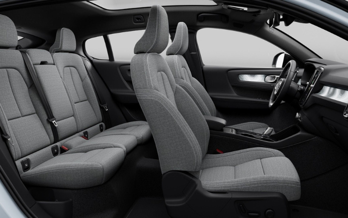 Interior view of a modern car featuring grey fabric seats with headrests, a spacious seating layout including the front and rear seats, a black centre console with gear shift, and a sleek dashboard with a steering wheel and digital display, showcasing a clean and contemporary design, ideal for used cars and new cars buyers.