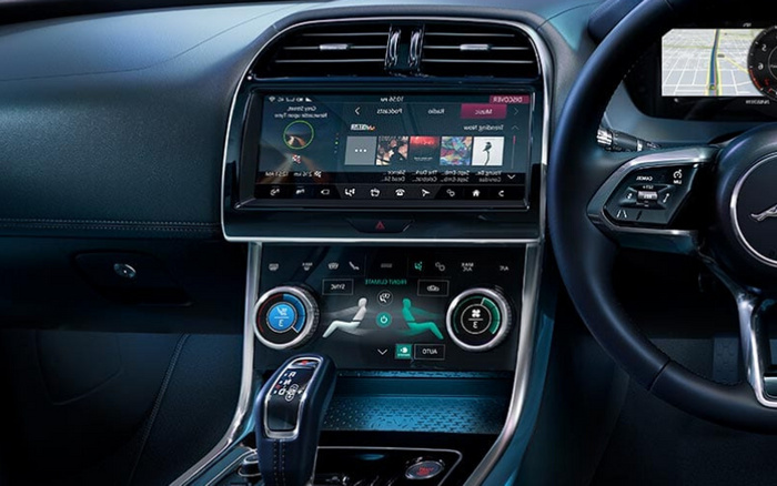 Interior view of a modern car dashboard showcasing digital touchscreen controls for music, climate control, and navigation. The display includes audio playback with tracks and playlists visible, alongside dual-zone climate settings with temperature controls and seat heating options. The gear selector and part of the steering wheel with multifunction buttons are also visible, highlighting advanced features typical in used cars and new cars.