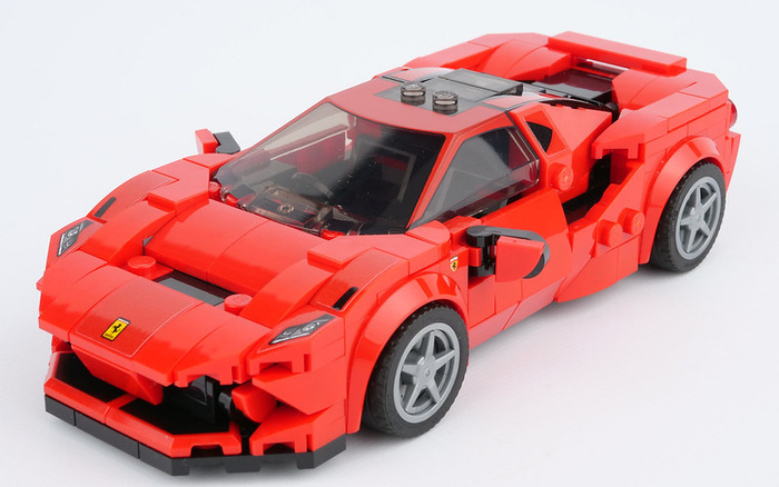 Red LEGO model of a Ferrari sports car showcasing detailed design, including realistic wheels, side mirrors, and Ferrari logo. The image emphasizes the intricate assembly and craftsmanship of the toy car, suitable for illustrating concepts related to new cars and used cars in automotive discussions.