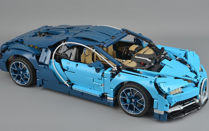 Detailed model of a blue sports car constructed from interlocking plastic bricks, showcasing intricate parts such as realistic wheels, aerodynamic design, front grille, and beige interior seats. The model represents a high-performance vehicle, suitable for illustrating concepts of used cars and new cars in automotive contexts.
