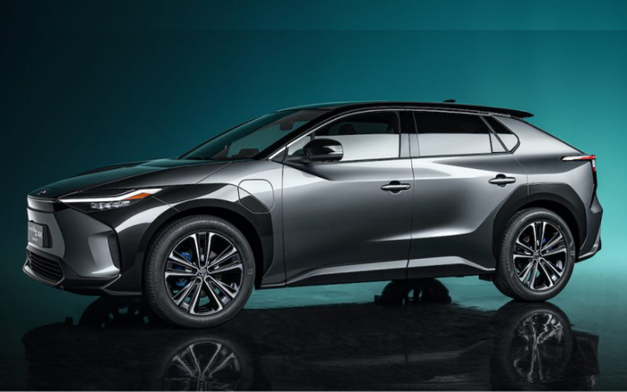 Sleek grey modern electric car shown from side view with aerodynamic design against teal background, highlighting smooth contours and black alloy wheels, representing a choice among used cars and new cars.