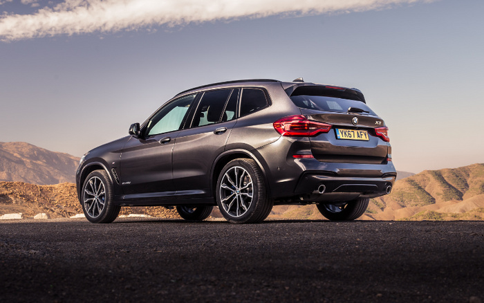 Black BMW X3 SUV parked on an asphalt road with mountainous landscape in the background, rear and side view showing UK license plate YK67 AFY, suitable for used cars and new cars advertising.