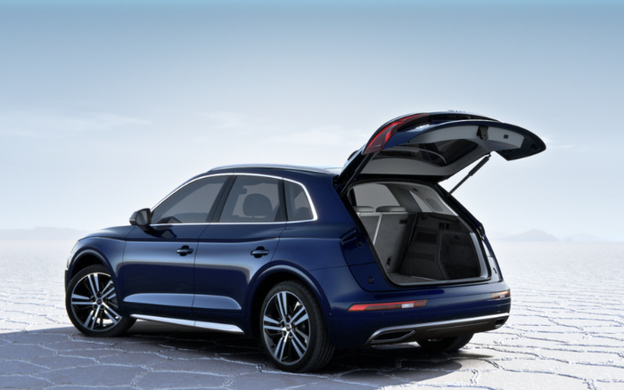Dark blue luxury SUV with rear hatch open, showing spacious empty boot, parked on cracked dry ground under clear sky, suitable for used cars or new cars advertisement.