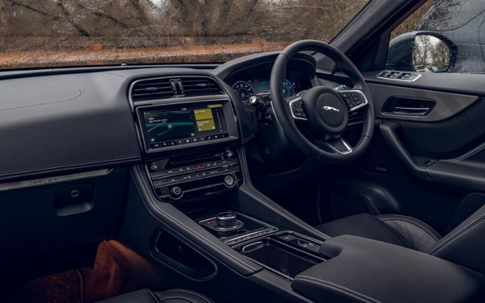Interior view of a Jaguar car showcasing the dashboard, steering wheel with Jaguar logo, central touchscreen displaying navigation, and various control buttons. The image highlights the modern, sleek design of the vehicle's cabin, suitable for both used cars and new cars markets.