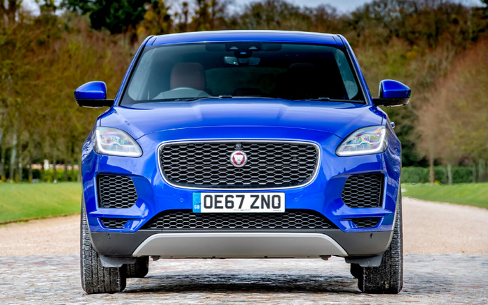 Front view of a blue Jaguar SUV with registration plate OE67 ZNO parked on a cobblestone road with grass and trees in the background, representing used cars and new cars for sale.