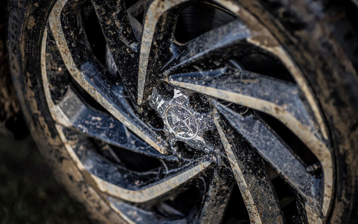 Close-up of a muddy car wheel rim featuring the Vauxhall logo at its centre, suitable for advertising used cars and new cars.