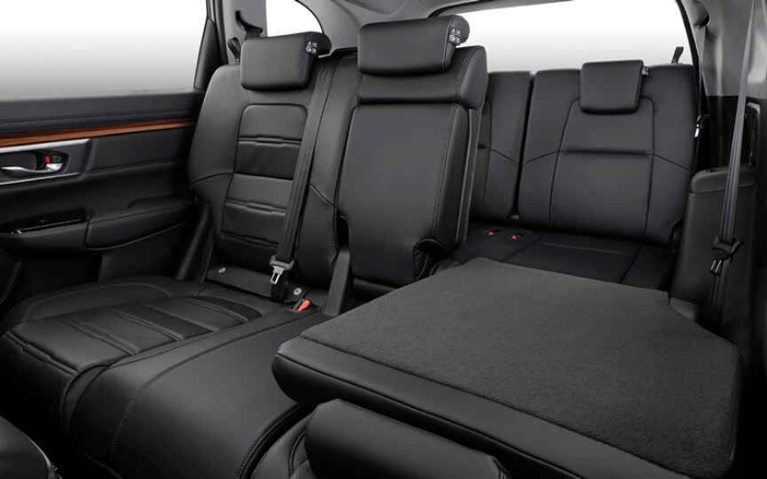 Interior view of a vehicle showcasing the back seats with black leather upholstery. The rear seats include headrests and seatbelts with a portion of one seat folded down to reveal the extended cargo space. The door panel features a combination of black material and a wooden accent trim. This clean and modern interior highlights comfort and practicality, relevant for used cars and new cars markets.