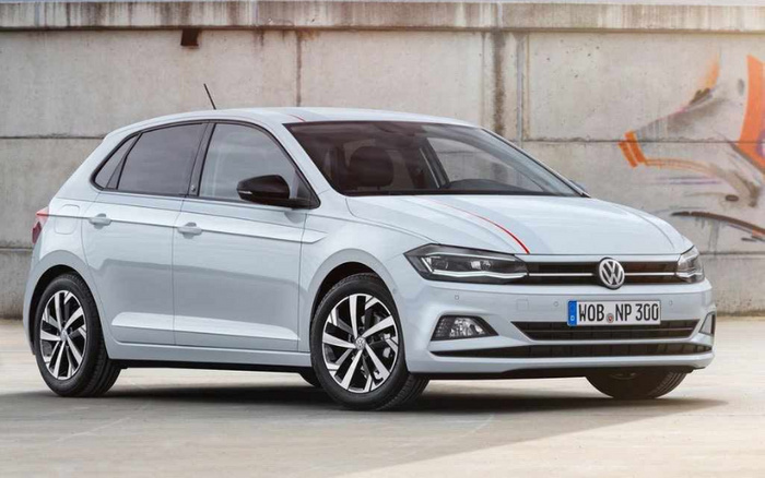 White Volkswagen Polo hatchback parked indoors in front of a concrete wall with graffiti. The car features modern LED headlights, black side mirrors, and stylish alloy wheels. The license plate reads 'WOB NP 300'. Ideal representation of both used cars and new cars in great condition.